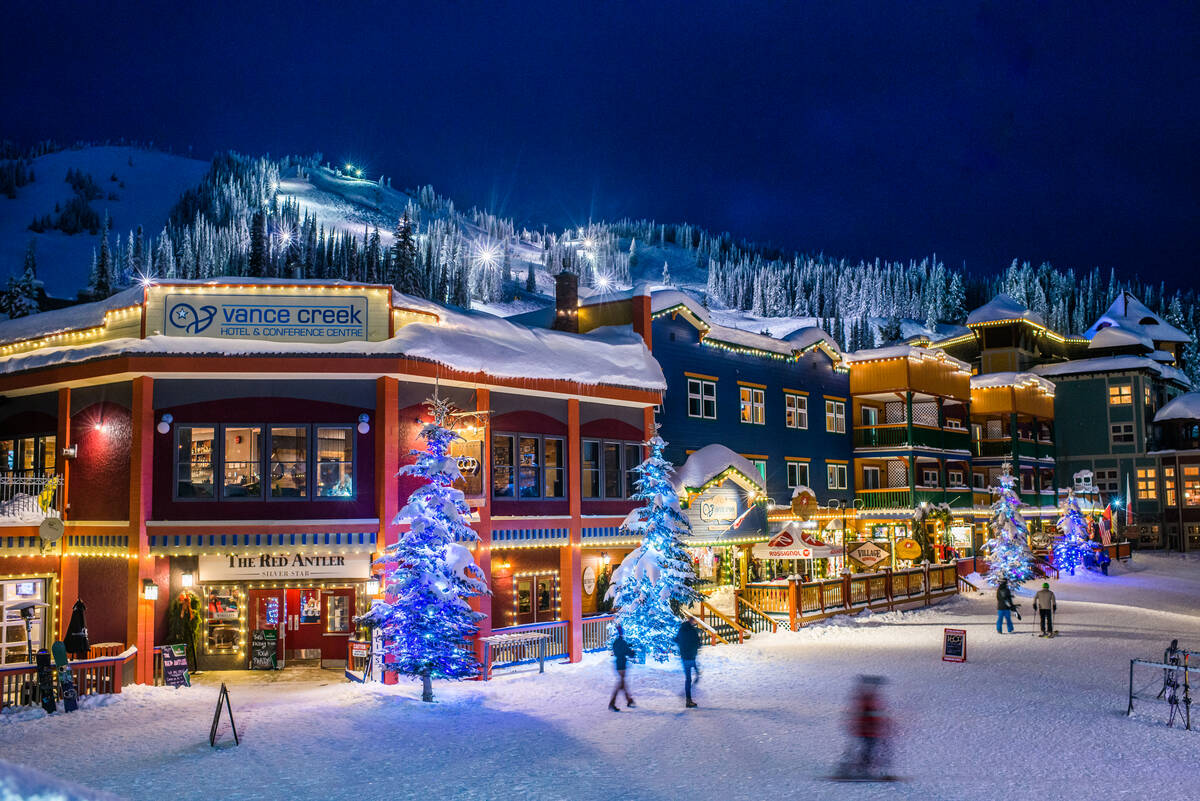 A night shot of SilverStar Mountain Resort's ski village with the mountain looming in the background.