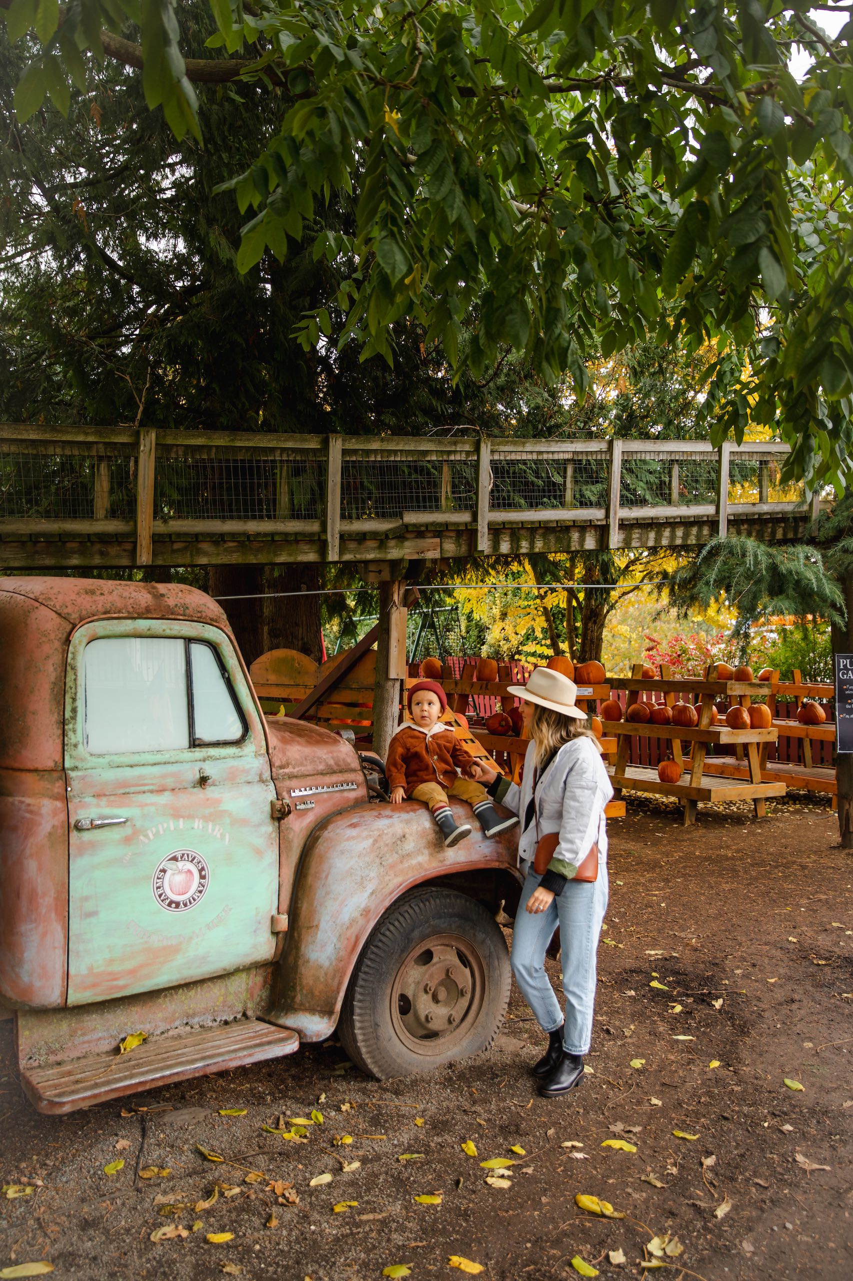 A mom and baby leaning on a old truck at Taves Farms