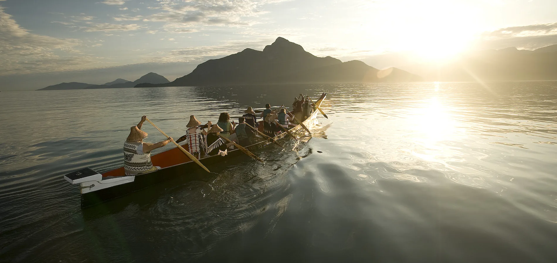 A group with Takaya Tours, rowing a traditional First Nations canoe in Howe Sound with mountains in the background.