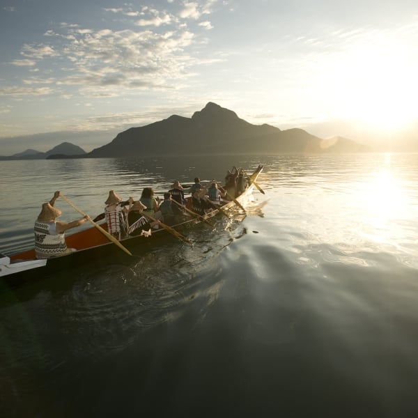 Un grupo con Takaya Tours, remando una canoa tradicional de las Primeras Naciones en Howe Sound con montañas al fondo.