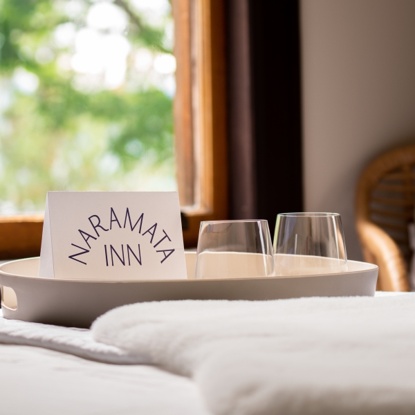 A close up of a tray on a bed with a notecard that reads, 
