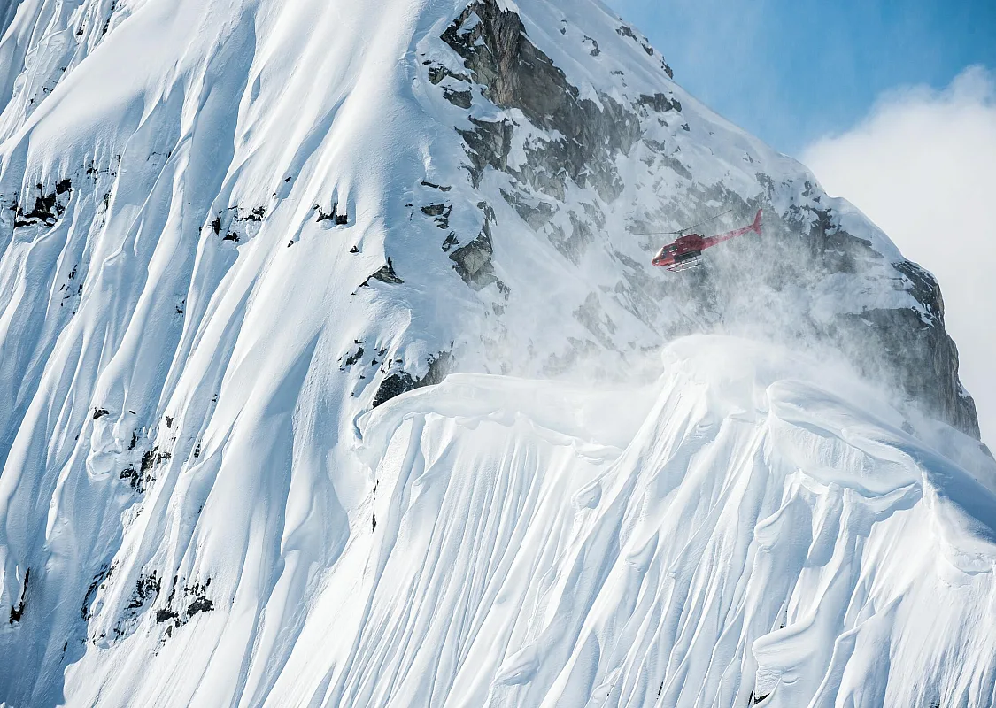 Un helicóptero de heliesquí sobrevolando una montaña cerca del Mica Heli Skiing Lodge.