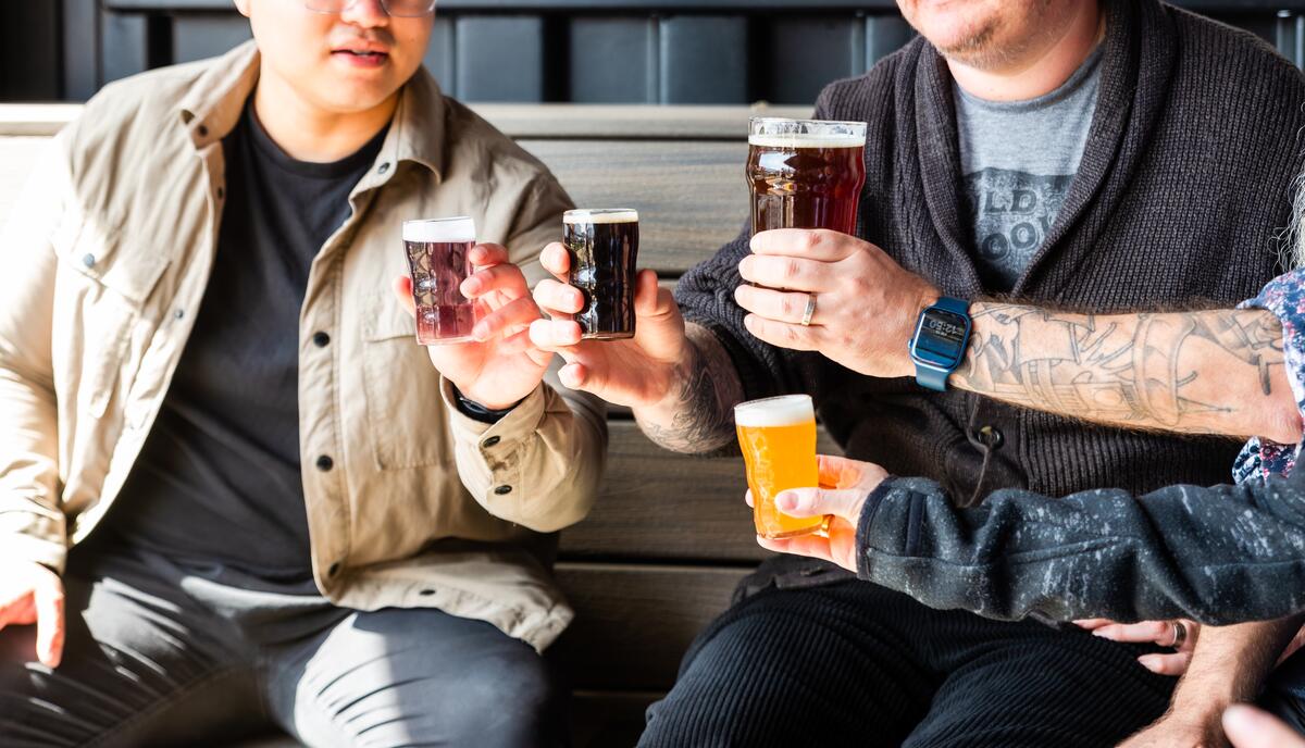 Group of people doing a cheers with beers at a brewery in Kelowna.