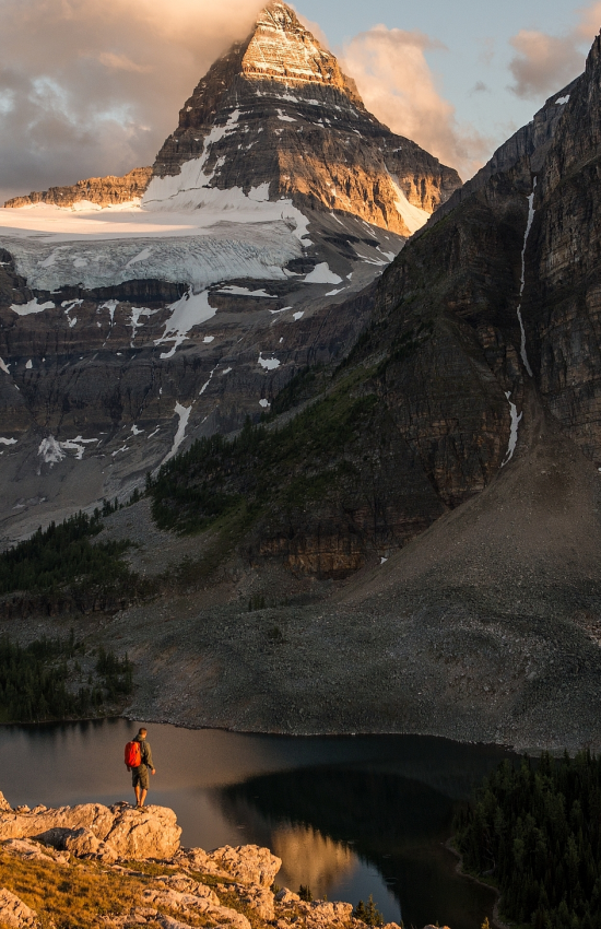 Una persona de pie frente a una gran montaña en BC, Canadá.