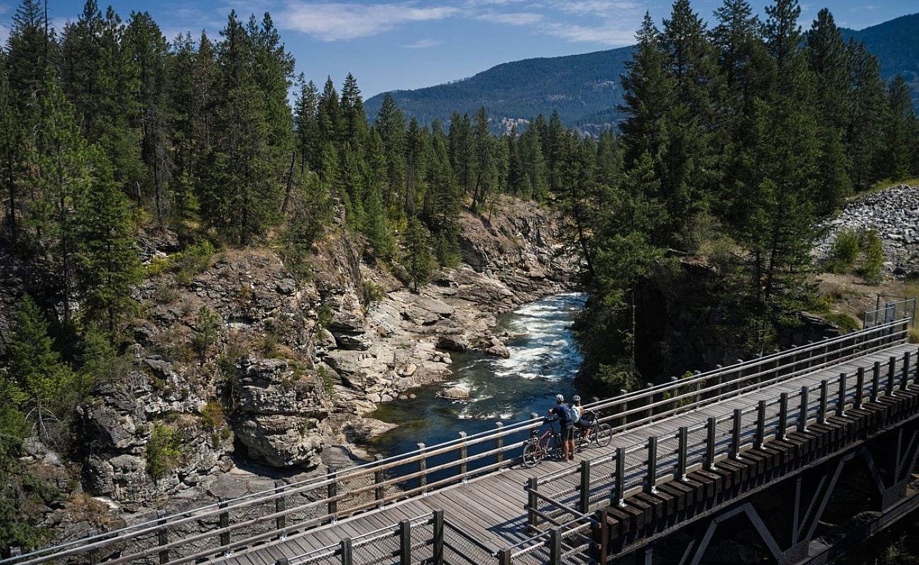 People looking at a river while taking a rest on their bikes