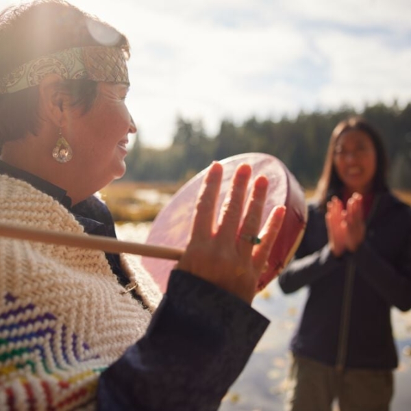Candace Campo from Talaysay Walking Indigenous Tours is conducting a presentation and speaking to a group while on a walking experience in Stanley Park in Vancouver.