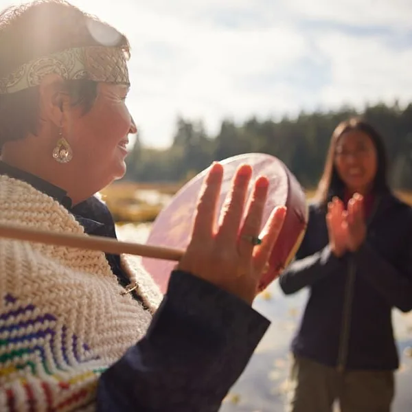 Candace Campo from Talaysay Walking Indigenous Tours is conducting a presentation and speaking to a group while on a walking experience in Stanley Park in Vancouver.