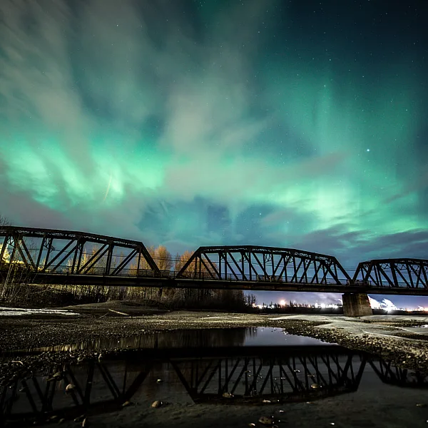 The Northern Lights are seen over an old train bridge in Prince George