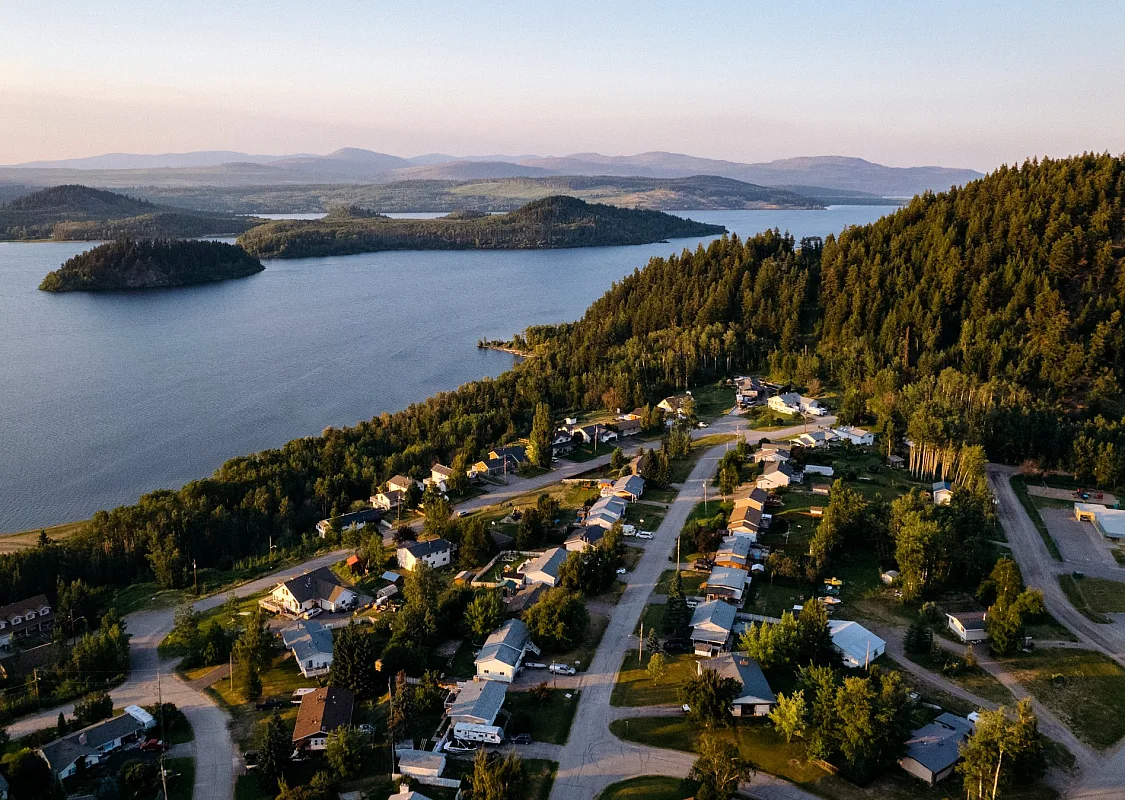 Aerial view of Mouse Mountain and Fraser Lake. Homes dot the residential streets. There is a tree covered hill behind then town.