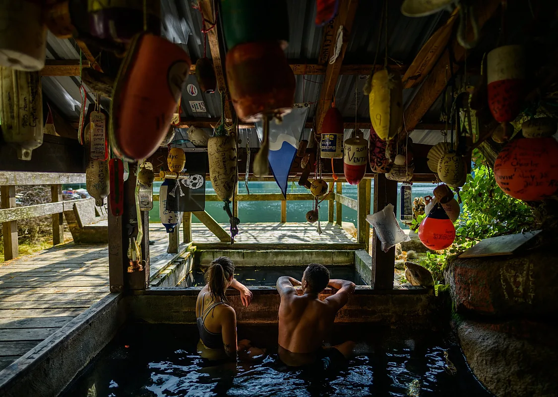 People soak in wooden hot springs tubs with fishing floats strung across the ceiling.