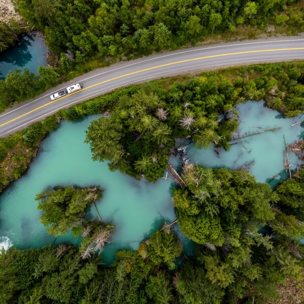 An aerial view of an RV driving through the Drowned Forest, a sea of turquoise water with forest growing into it.