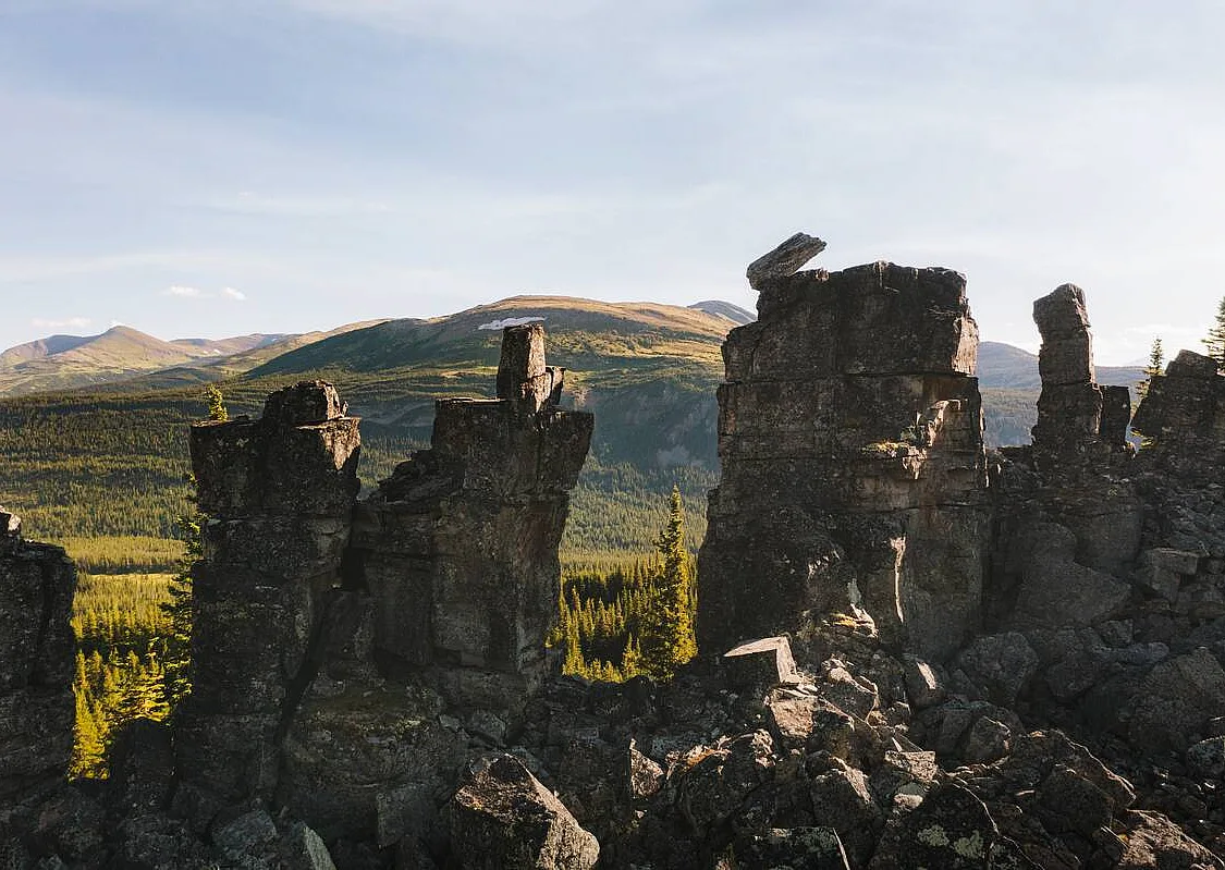 A variety of rocks stacked on one another in the shape of a ship's smokestacks with a lush boreal forest in the background.