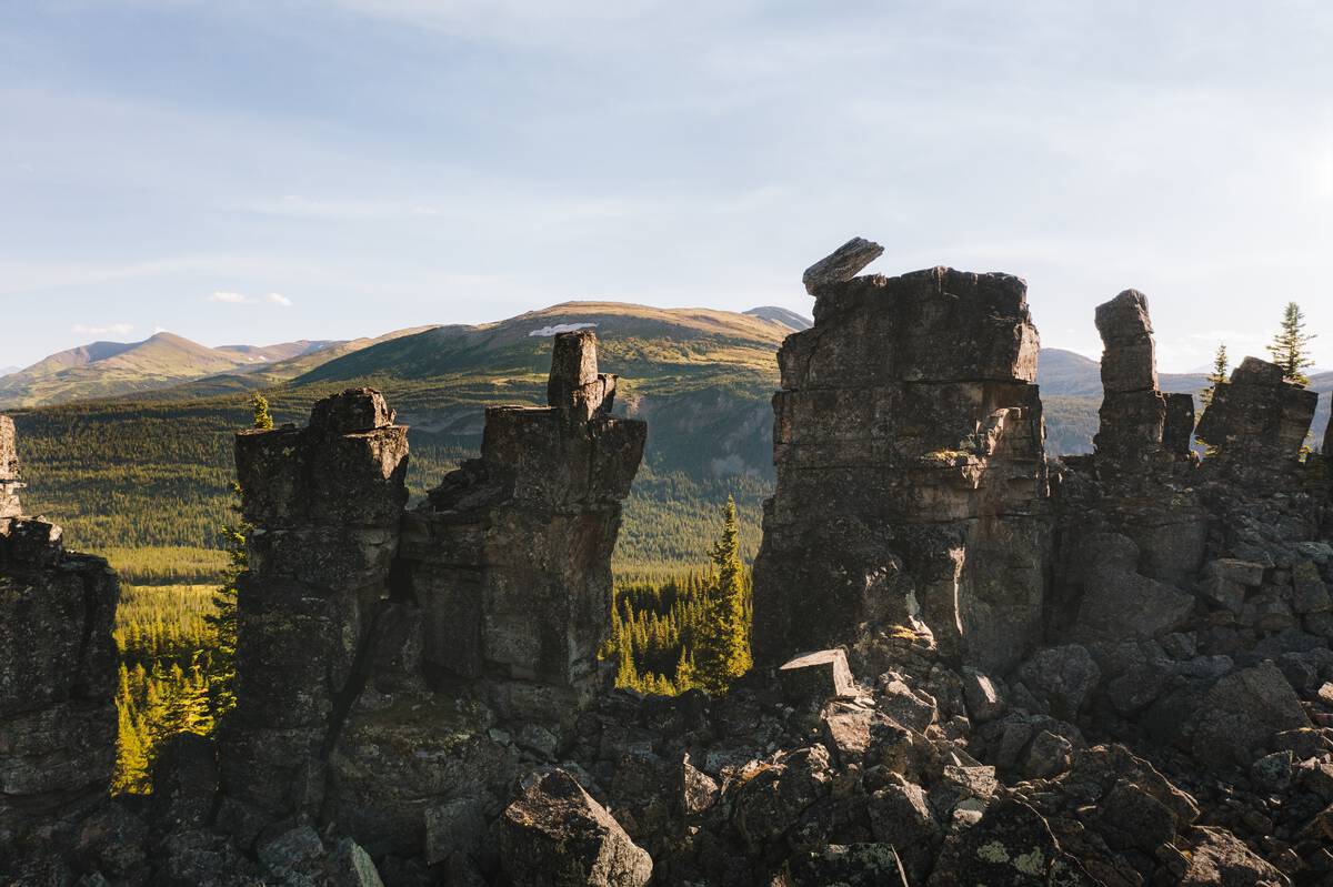 A variety of rocks stacked on one another in the shape of a ship's smokestacks with a lush boreal forest in the background.