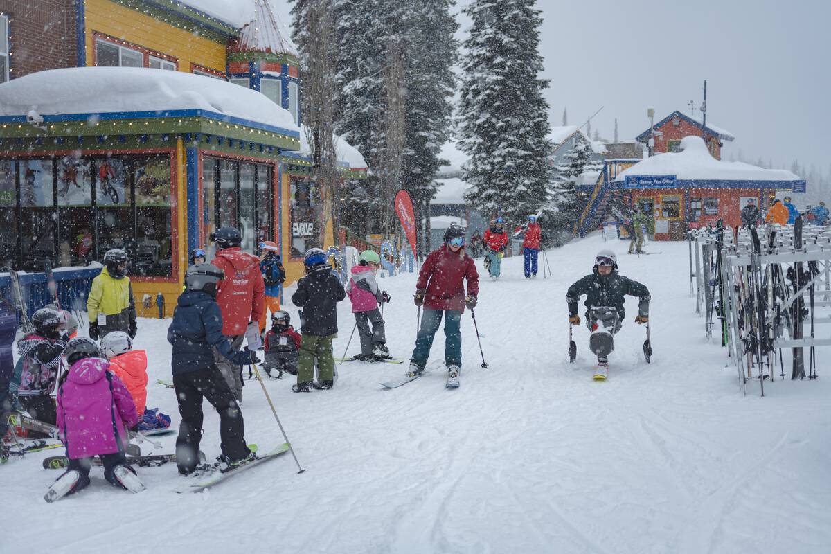 Adaptive skier crossing through SilverStar Mountain Resort village area during snowfall.