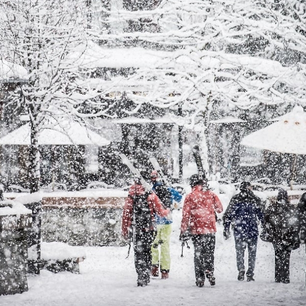 Skiers walk down a snowy street in Whistler.