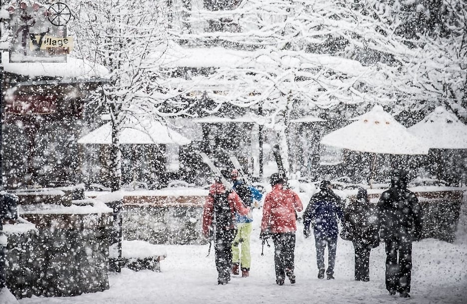 Skiers walk down a snowy street in Whistler.