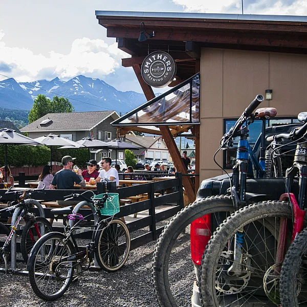 A group of mountain bikers enjoys a patio pint at a local brewery with bikes parked out front.