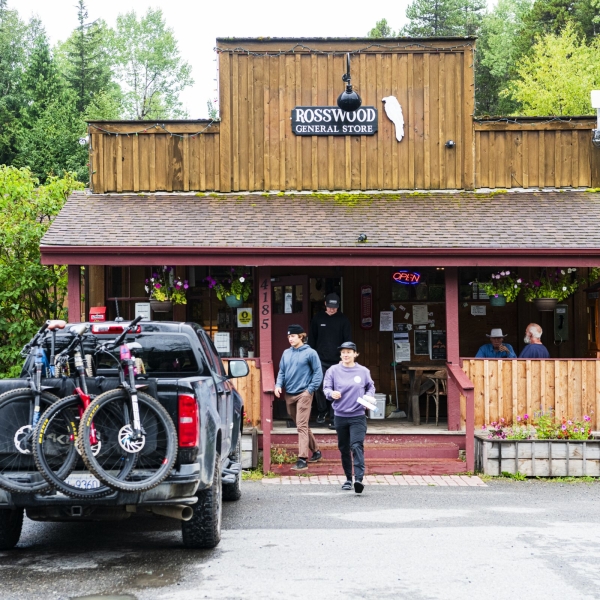 Dos personas salen de una tienda de abarrotes hacia su camioneta, que lleva bicicletas de montaña.
