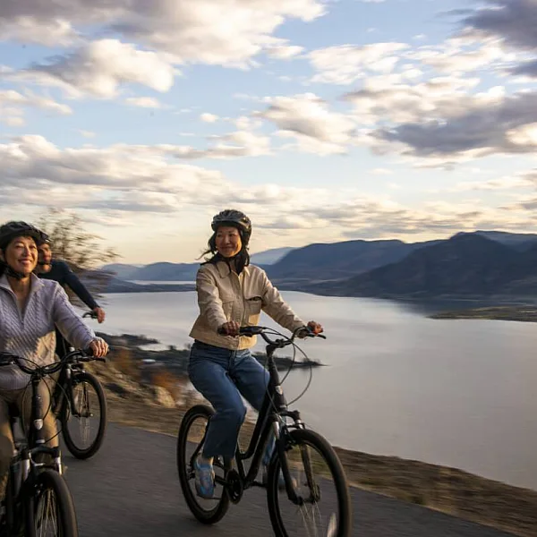 Eine Familie genießt eine Radtour am Okanagan-See entlang auf dem Kettle Valley Rail Trail in Naramata.