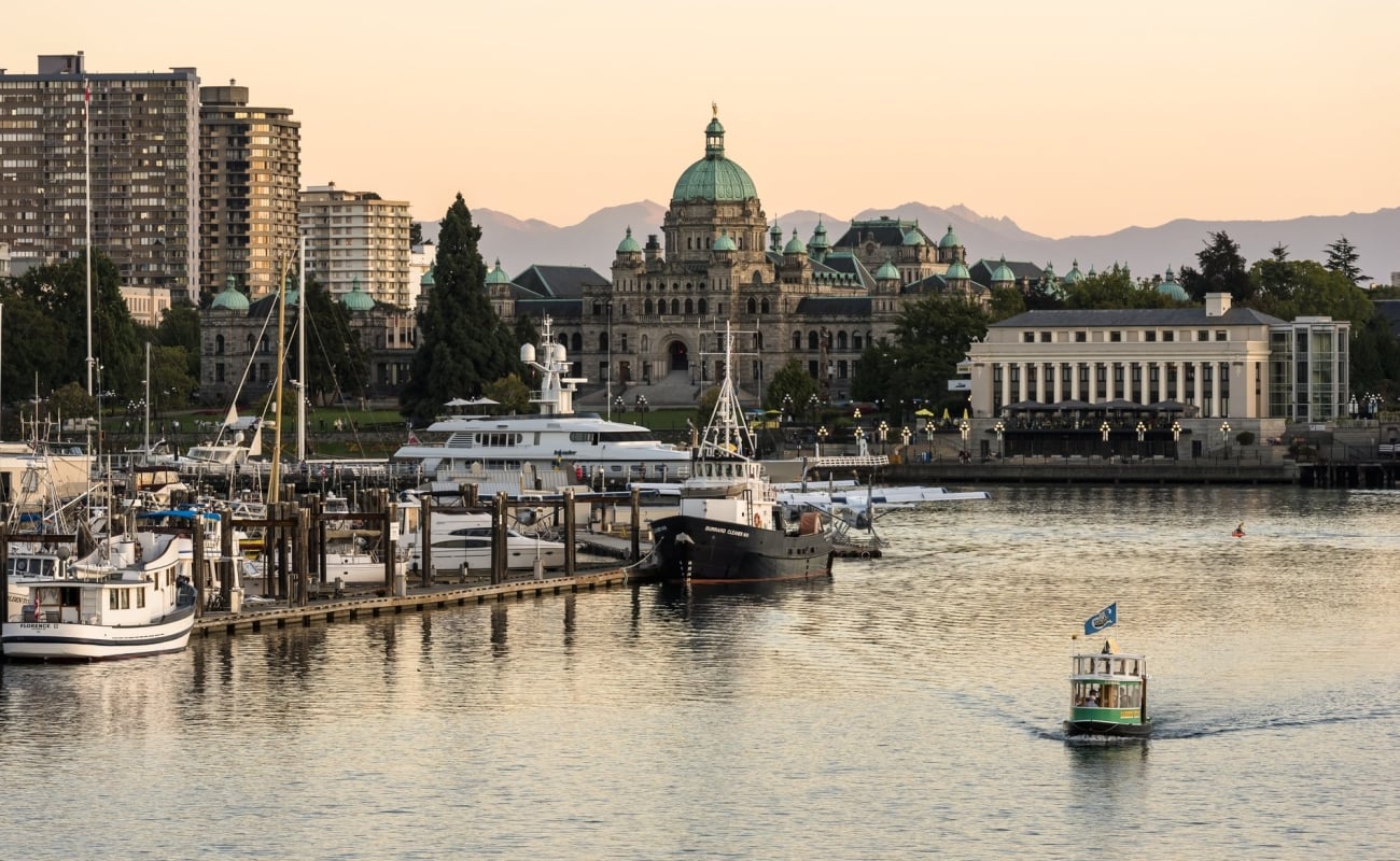 Victoria's Inner Harbour as a boat taxi cruises along the water and the sunsets