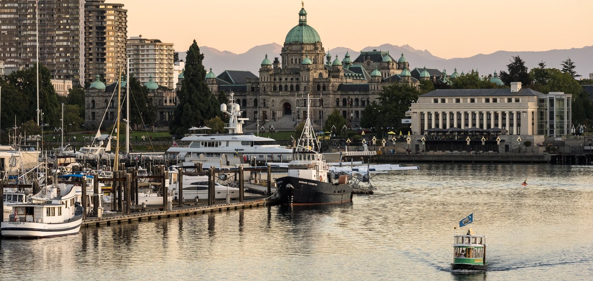 Victorias Inner Harbour, während ein Wassertaxi über das Wasser fährt und die Sonne untergeht.