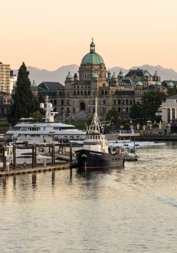 Victoria's Inner Harbour as a boat taxi cruises along the water and the sunsets
