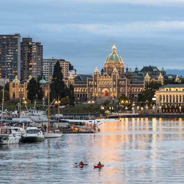 The downtown harbour front of Victoria at night. The lights are on at the BC Parliament Buildings, reflecting on the water.