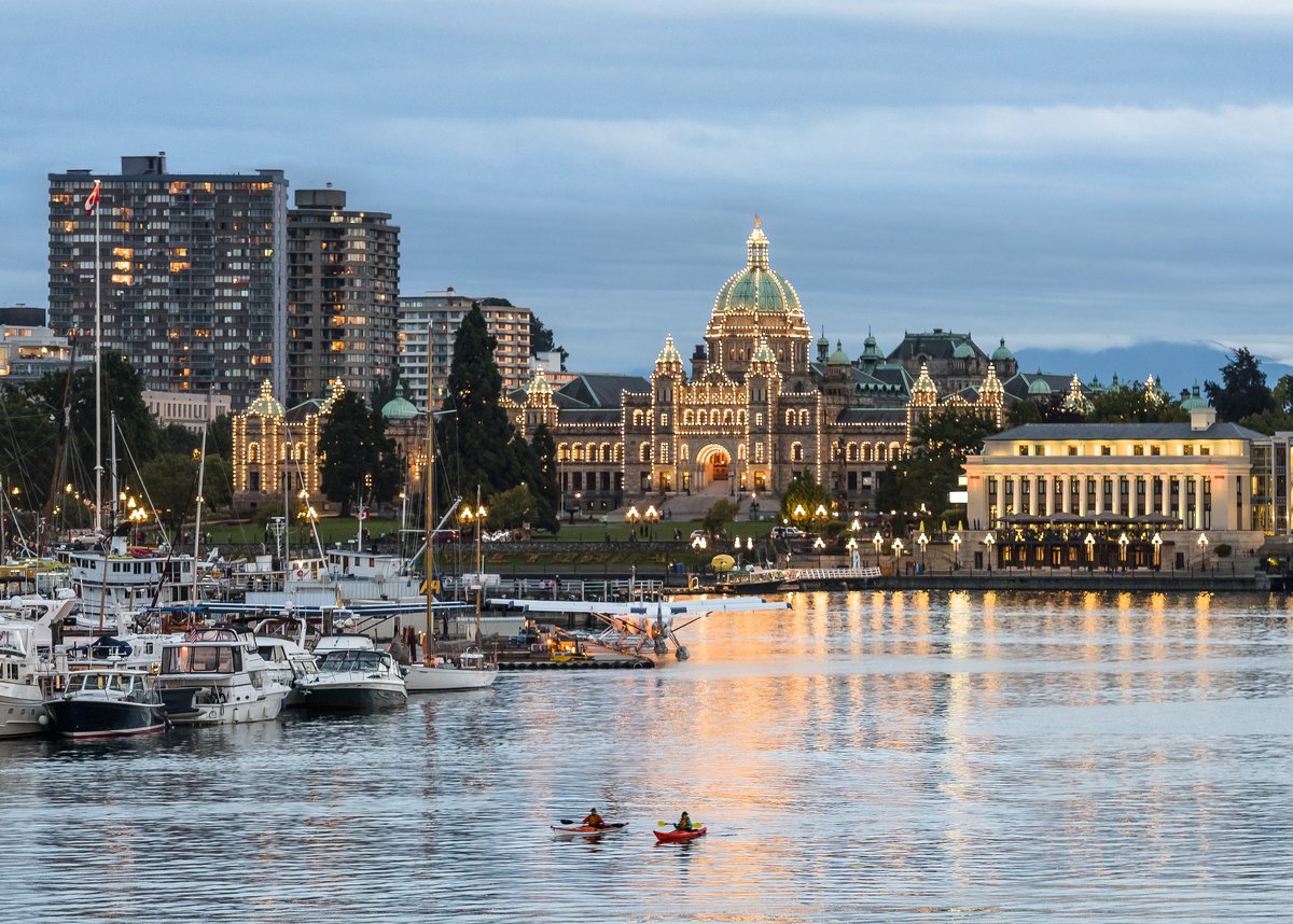 The downtown harbour front of Victoria at night. The lights are on at the BC Parliament Buildings, reflecting on the water.
