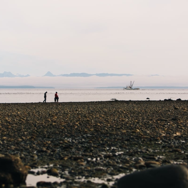 Two people walk along the beach in the distance