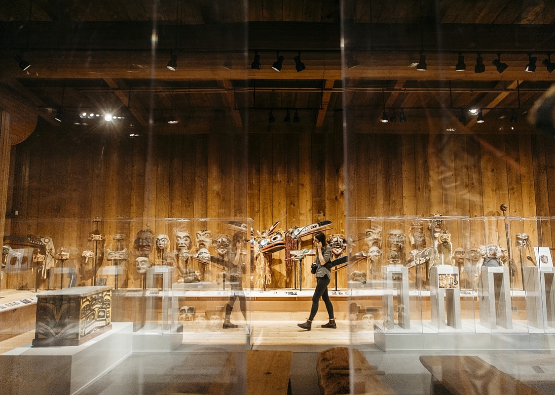 Una persona camina por el U'Mista Cultural Centre con arte indígena en exhibición detrás de paneles de vidrio | Nathan Martin