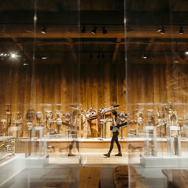 Una persona camina por el U'Mista Cultural Centre con arte indígena en exhibición detrás de paneles de vidrio | Nathan Martin