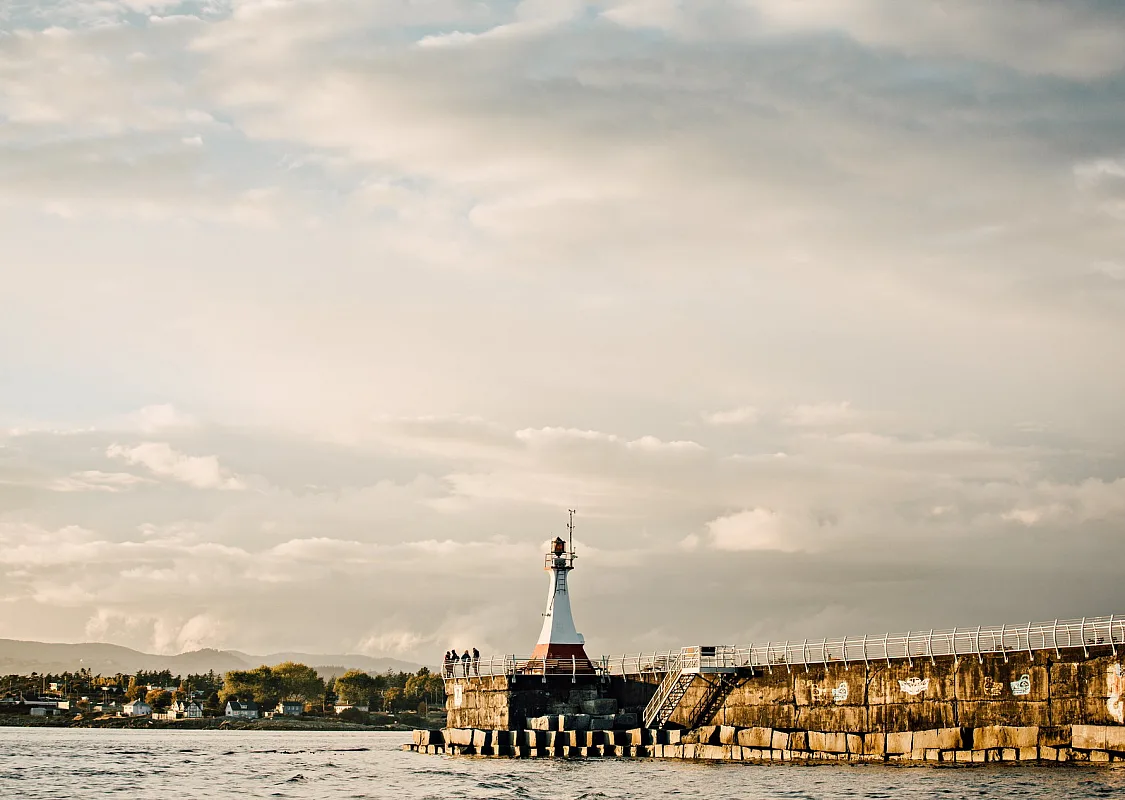 Ogden Point Breakwater in Victoria. The sun is starting to set in the cloudy sky.