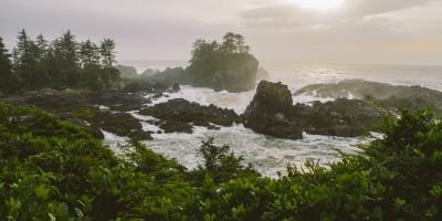 Sunrise at Wild Pacific Trail, the Coast of Vancouver Island in Ucluelet. The waves crash long the rocky shoreline and several small rocky outcrops are in the water.