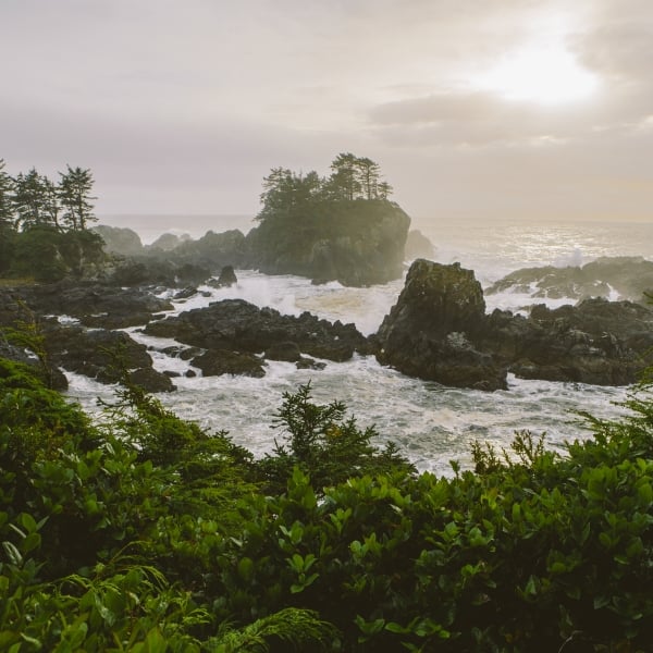 Sunrise at Wild Pacific Trail, the Coast of Vancouver Island in Ucluelet. The waves crash long the rocky shoreline and several small rocky outcrops are in the water.