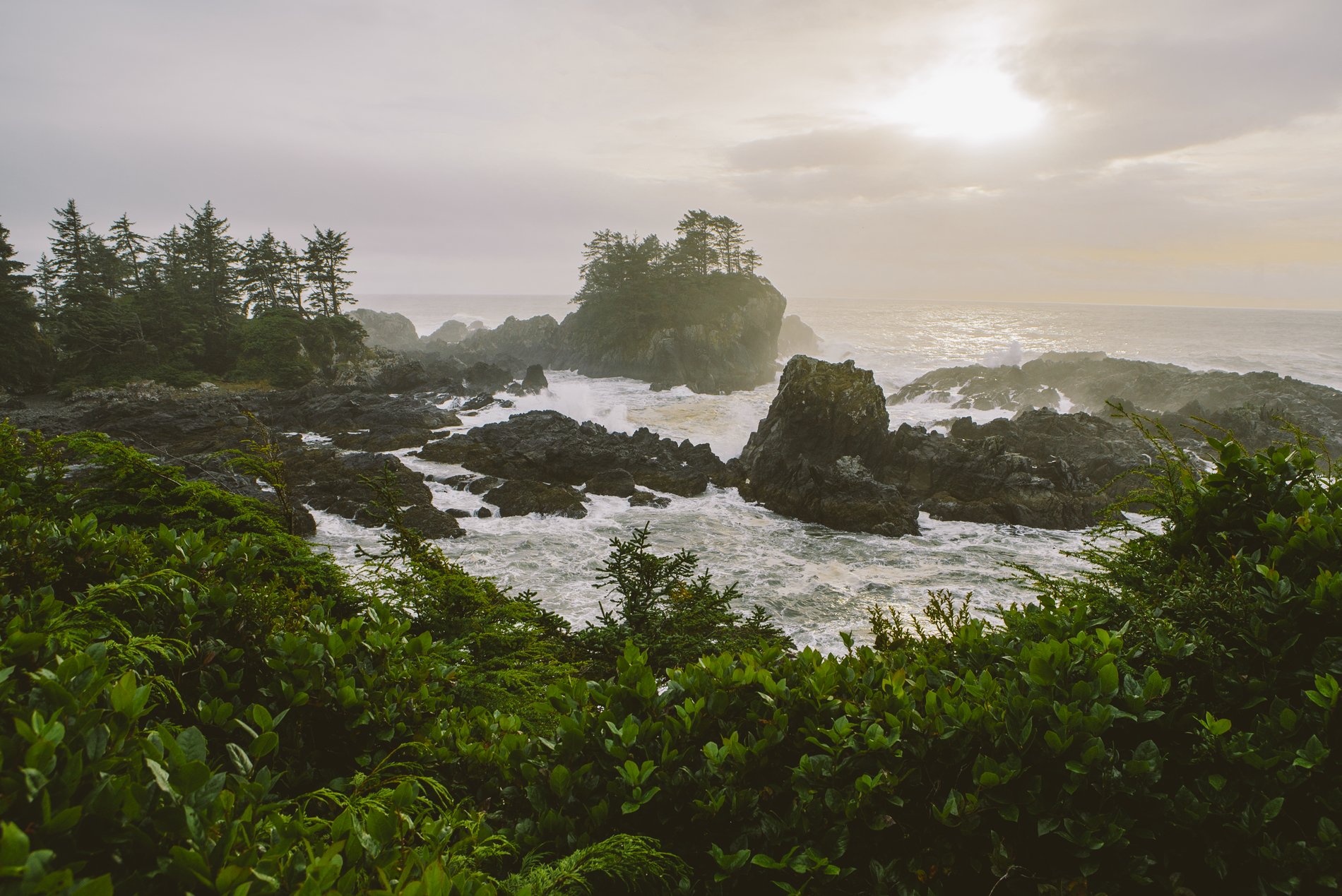 Sunrise at Wild Pacific Trail, the Coast of Vancouver Island in Ucluelet. The waves crash long the rocky shoreline and several small rocky outcrops are in the water.