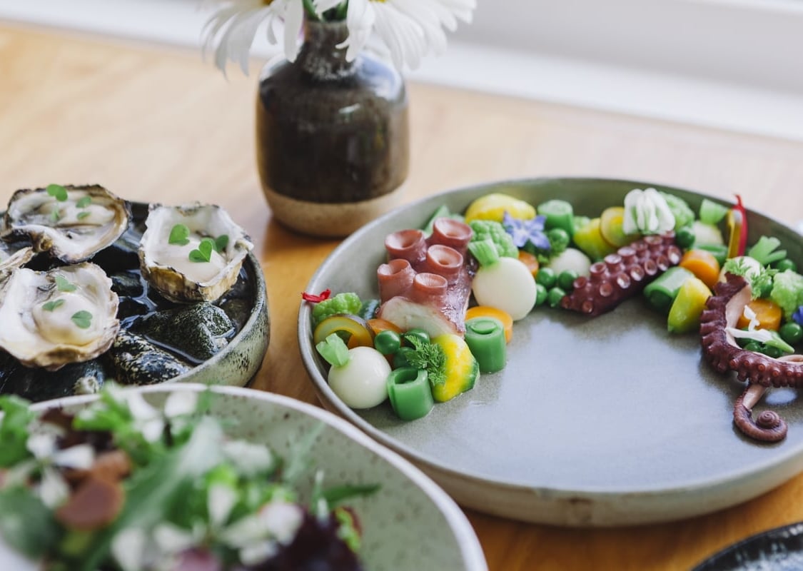 Tres platos de mariscos en una mesa de madera con una variedad de sushi y otros elementos.