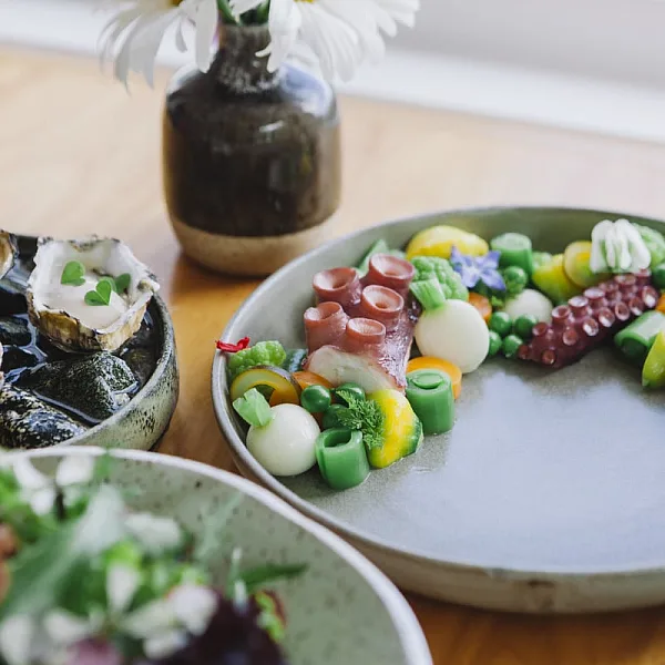 Three dishes of seafood on a wooden table with an assortment of sushi and other items.
