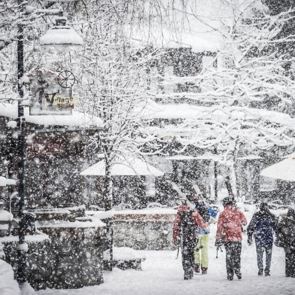 a snowy whistler village with people walking on the pedestrian streets