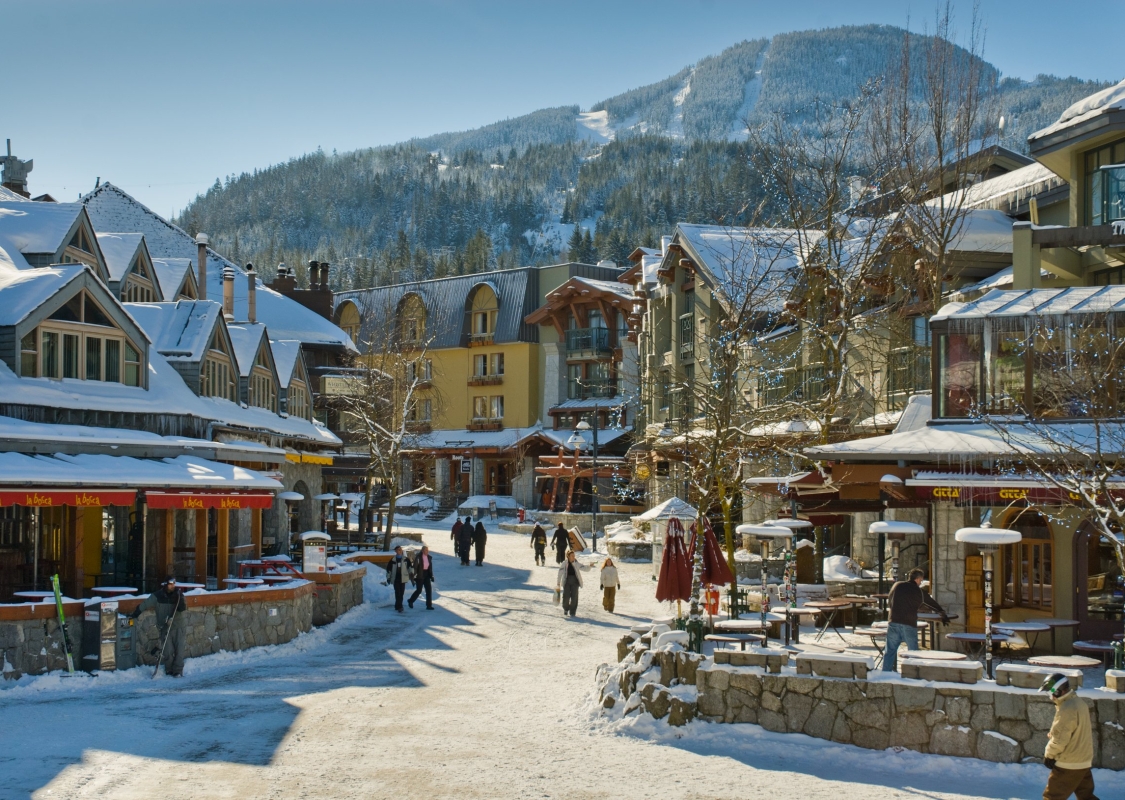 Gente caminando por Whistler Village en invierno, con los edificios cubiertos de nieve.