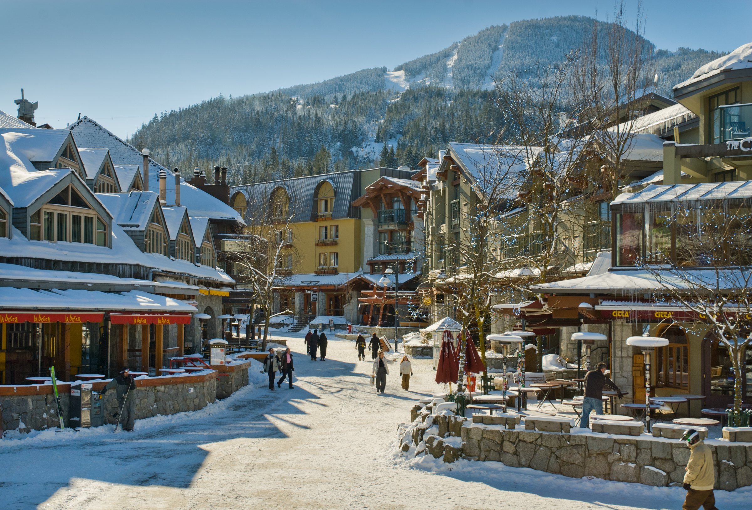 People walking through Whistler Village in winter with snow covered buildings.