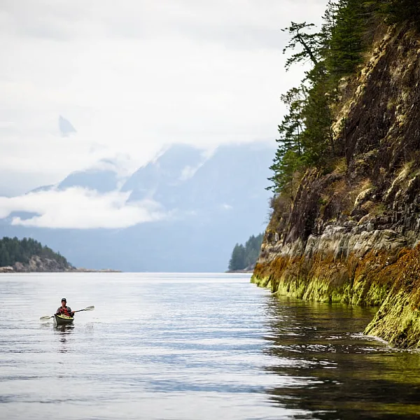 A kayaker paddles along the coastline of Desolation Sound at low tide.