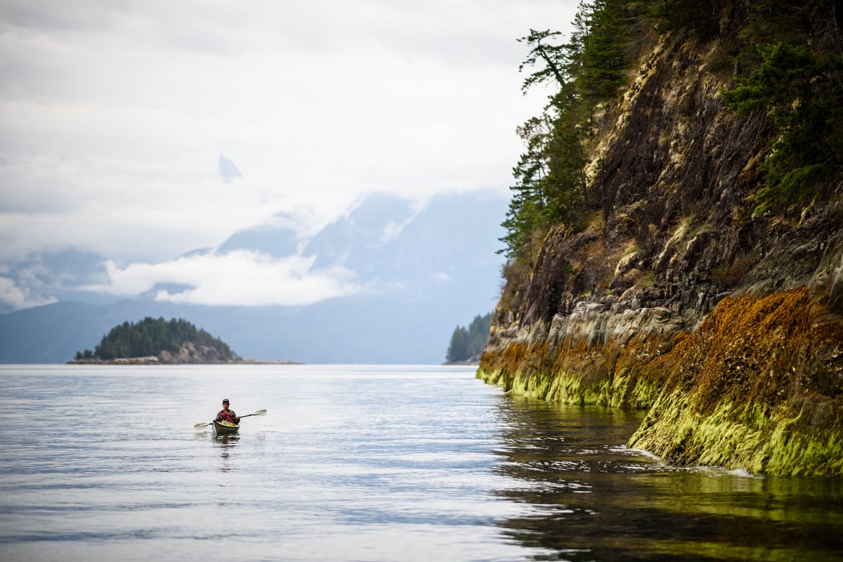 A kayaker paddles along the coastline of Desolation Sound at low tide.