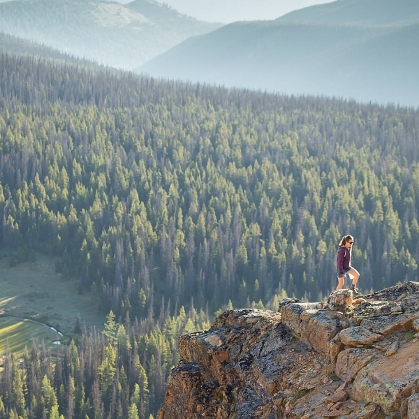 A person stands on a rock ledge looking out at the views below in Cathedral Provincial Park.