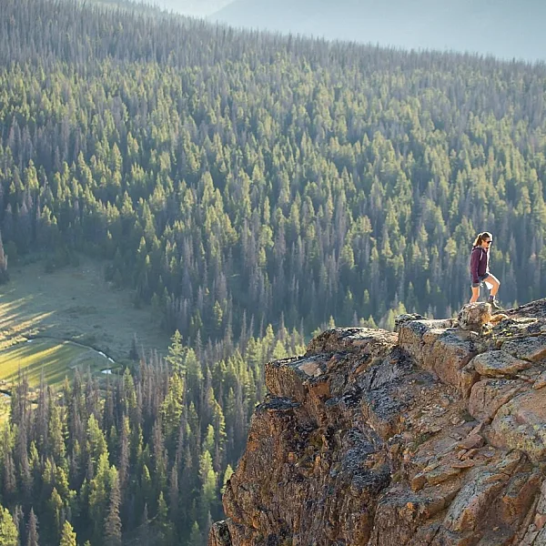 Eine Person steht auf einem Felsvorsprung und blickt auf die Aussicht unter sich im Cathedral Provincial Park.