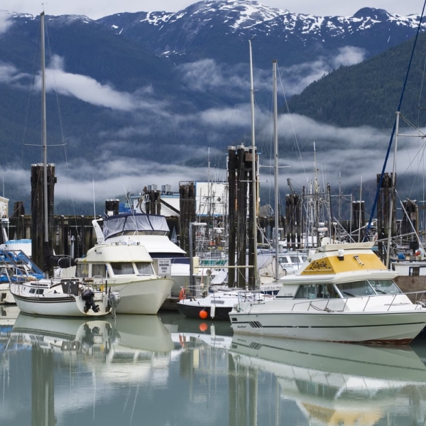 Boats in the harbour on a sunny day at the Bella Coola Marina, mountains behind with a touch of snow at the peaks