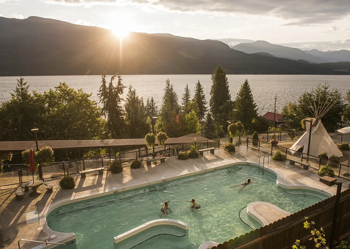 Bathers enjoy simming at Ainsworth Hot Springs with a view of Kootenay Lake