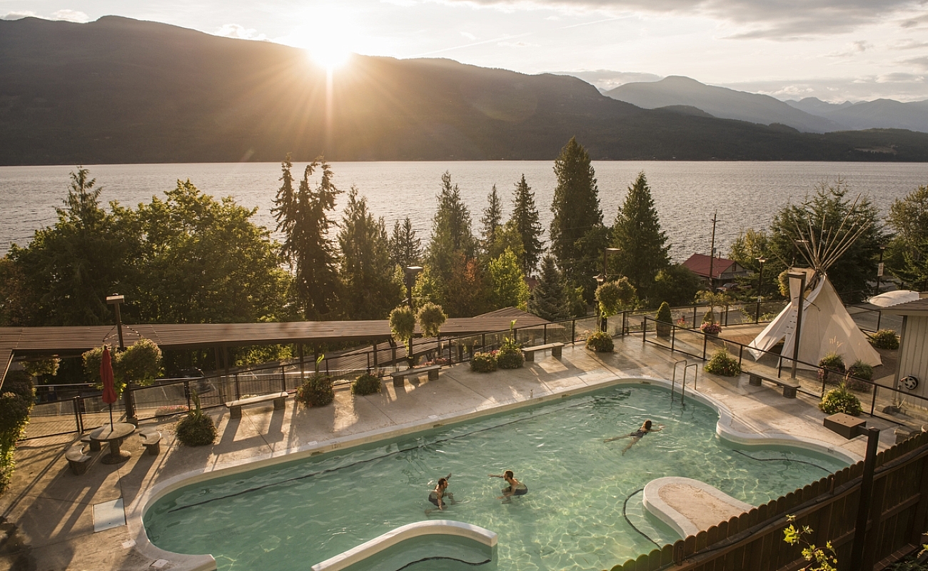 Bathers enjoy simming at Ainsworth Hot Springs with a view of Kootenay Lake