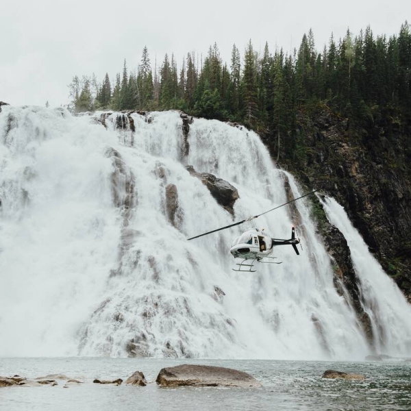 A helicopter flies low beside the spectacular 70-metre high Kinuseo Falls..