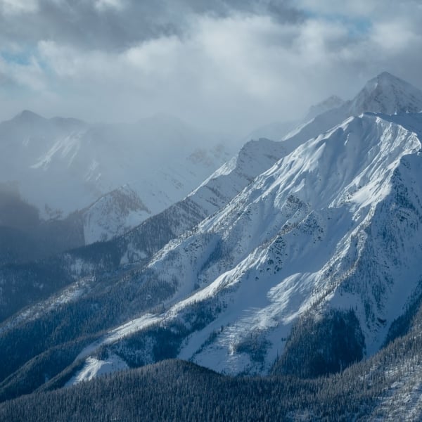 Aerial view of imposing, snow-covered mountains with a foggy sky