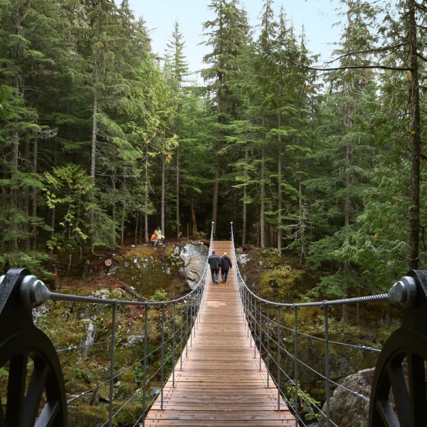 Two people walk over a suspension bridge in Whistler